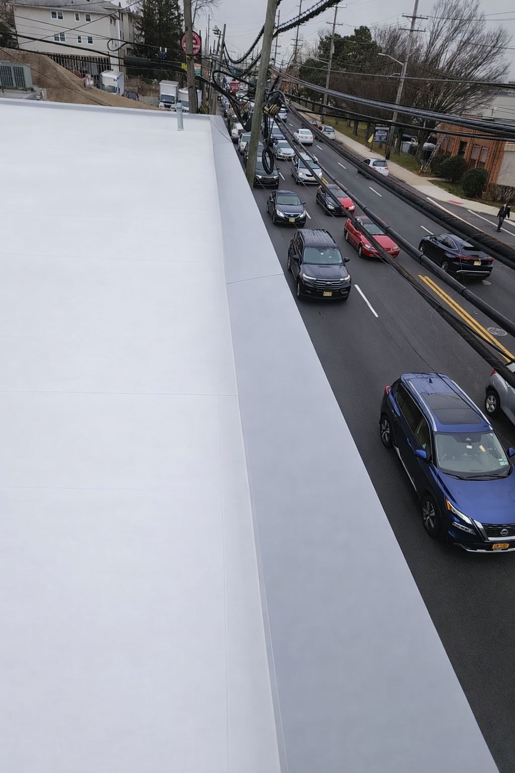Completed white membrane roof next to a busy road